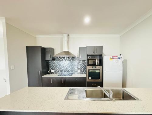 a kitchen with a sink and a white refrigerator at Cozy Share Suite in Coopers Plains - Double Room with Private Bathroom in Brisbane