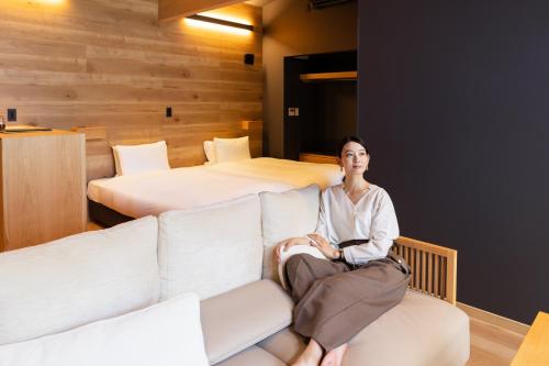 a woman sitting on a couch in a room with two beds at 7c villa and winery in Fujikawaguchiko