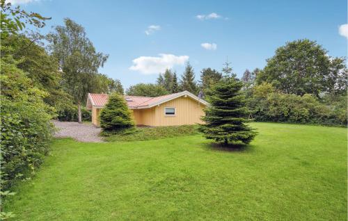 a house with two pine trees in a yard at Holiday Home Valmuevej Tranekær Denm in Skattebølle