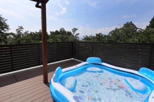 a hot tub on a deck with an umbrella at Wellリゾート富士 in Gotemba