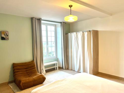 a bedroom with a bed and a chair in front of a window at The Chateau 45Pers, 30min from Sea in Amayé-sur-Orne