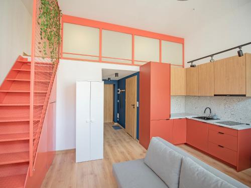 a kitchen with orange and white cabinets and a couch at 1 min from Main Square I Budget Apartment in Gliwice