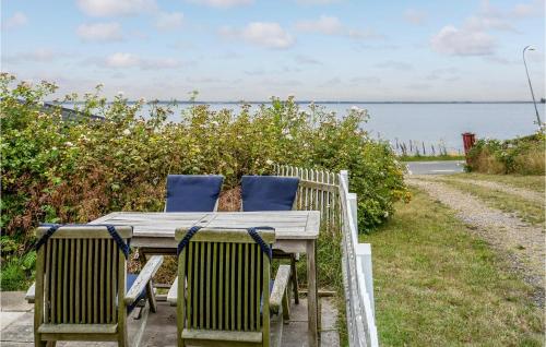 a wooden table and chairs with a view of the water at 2 Bedroom Nice Apartment In Skårup Fyn in Oure