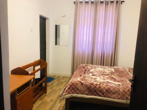 a bedroom with a bed and a desk and a window at R21 Nuwara Eliya in Nuwara Eliya