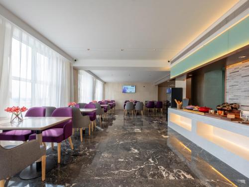 a restaurant with purple chairs and tables and a bar at Lavender Hotel Xinle Shijiazhuang Airport Hebei Academy of Fine Arts in Xinle