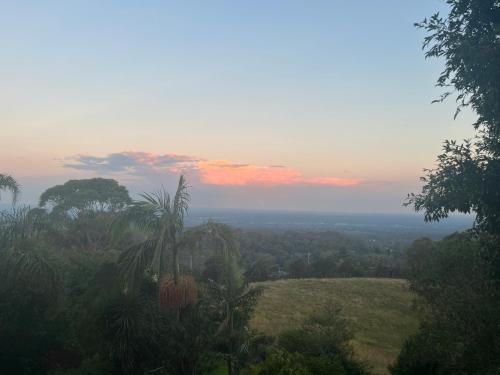 a view of a field with trees and a sunset at Mountain hideaway Blue Mountains in Kurrajong