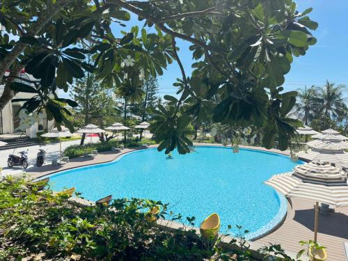 a large blue swimming pool with umbrellas and trees at Edensee Kega Beach Resort in Ke Ga