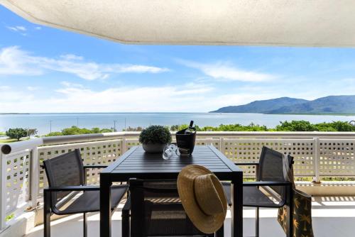 a table and chairs on a balcony with a view of the ocean at Belle Escapes Rydges Plaza Esplanade Luxury 2-Bedroom Apartment in Cairns North