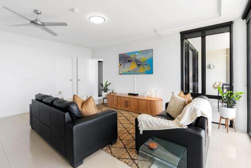 a living room with two black chairs and a table at Belle Escapes Rydges Plaza Esplanade Luxury 2-Bedroom Apartment in Cairns North