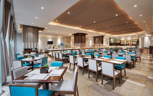 a dining room with tables and blue chairs at Green Beach Hotel Nha Trang in Nha Trang