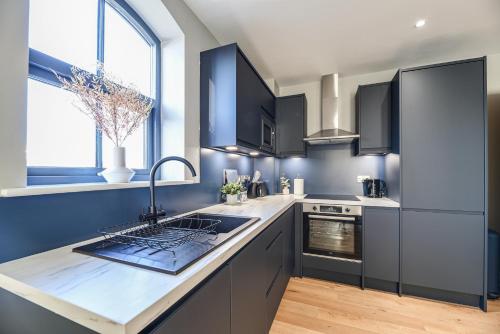 a kitchen with black cabinets and a counter top at Luxury Prime Location Manchester Flat in Manchester