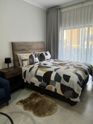 a bedroom with a black and white bed and a window at Cozy-corner in Gaborone