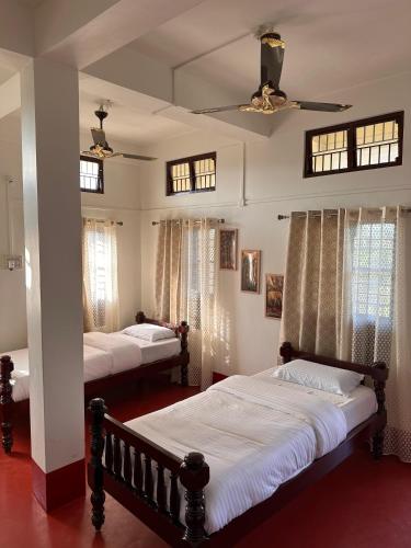 a bedroom with two beds and a ceiling fan at Protibha Homestay in Sivasagar