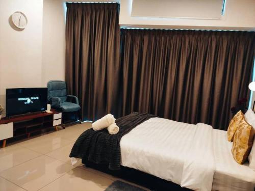 a bedroom with a bed and a chair and a television at Cozy Haven Perfect Studio Getaway in Petaling Jaya