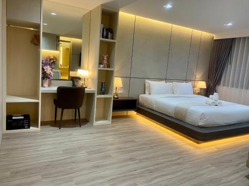 a bedroom with a bed and a desk and a chair at indigo Hotel Hatyai in Ban Kohong