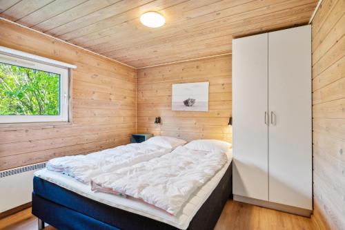 a bed in a wooden room with a window at Stunning Home In Knebel With 3 Bedrooms, Swimming Pool And Wifi in Knebel