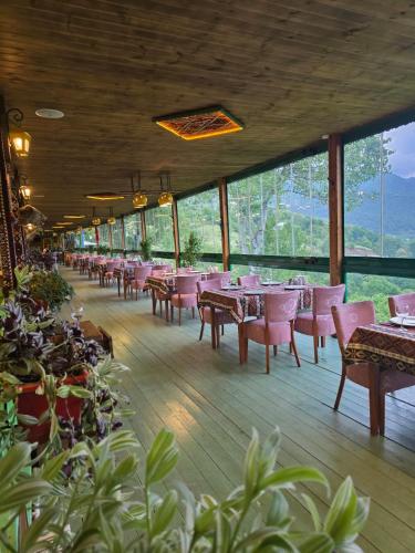 a dining room with tables and chairs and windows at Gabala Tufandag City Hotel in Gabala
