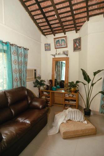 a living room with a leather couch and a mirror at Cozy Dream Apartment in Anjuna