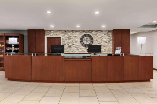 a lobby with a reception desk with a clock on the wall at Wyndham Garden Duluth in Duluth