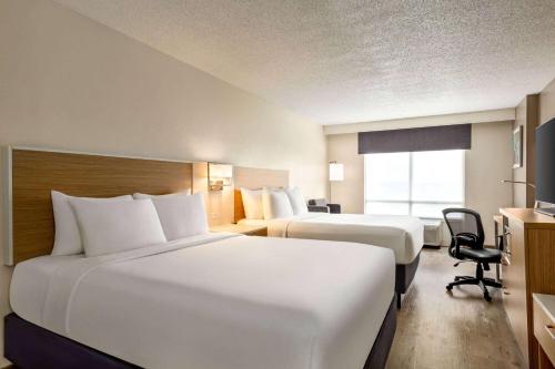 a hotel room with two beds and a desk at Wyndham Garden Duluth in Duluth