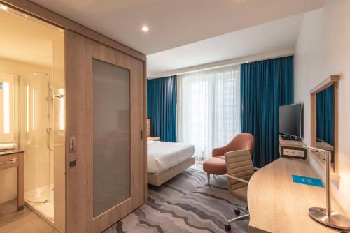 a hotel room with a bedroom with a bed and a desk at Hampton by Hilton Berlin City Centre Alexanderplatz in Berlin