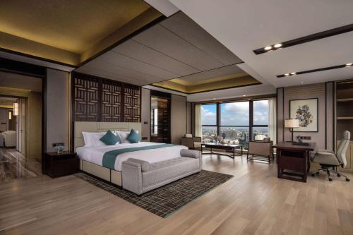 a bedroom with a king sized bed and a desk at Wyndham Grand Maoming in Maoming
