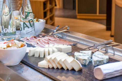 Una mesa repleta de quesos, carnes y botellas de vino. en The Originals Boutique, Hôtel Le Marmotel, Clermont-Ferrand, en Clermont-Ferrand