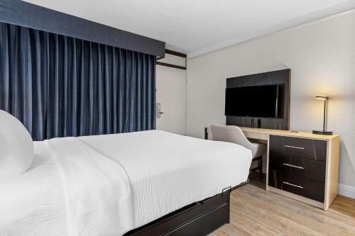 a hotel room with a bed and a flat screen tv at Suburban Studios Slidell I-10 in Slidell