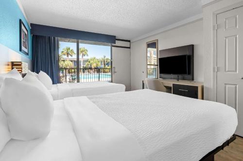 a hotel room with a large white bed and a television at Suburban Studios Slidell I-10 in Slidell