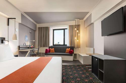 a hotel room with a bed and a couch at Vienna House Easy by Wyndham Bucharest Airport in Otopeni