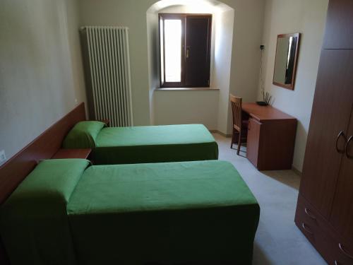 a room with two green beds and a desk at Antica Masseria Lo Conte in Ariano Irpino