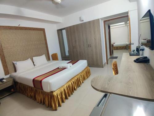 a bedroom with a large bed and a table at Cox West Inn in Cox's Bazar