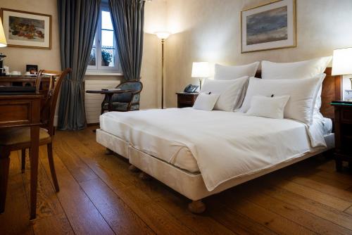 a bedroom with a large white bed and a desk at Domaine de Châteauvieux in Peney-Dessus