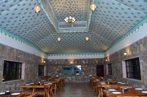 a dining room with wooden tables and a ceiling at Ananda Resort in Pushkar