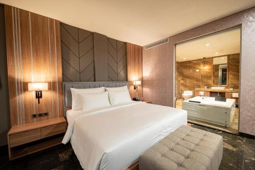 a bedroom with a large white bed and a bathroom at Taman Prakerti Bhuana Hotel in Gianyar