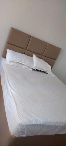 a bed with white sheets and two pillows at Joan's home to many in Kisumu