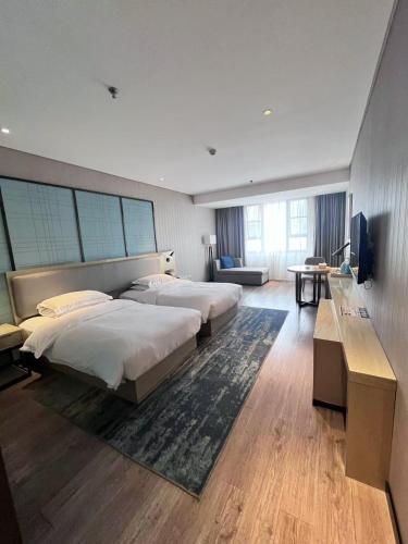 a hotel room with two beds and a television at Echarm Hotel Kunming Baita Road Huidu International Store in Kunming