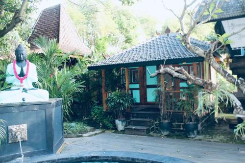 a statue of a buddha in front of a house at Resort JUNGLEROOM Canggu in Canggu