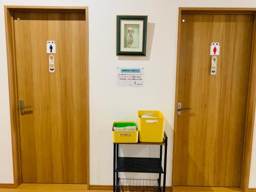 two wooden doors in a room with a shelf with a box at Village BFH in Omura