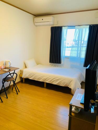 a room with two beds and a desk and a tv at Village BFH in Omura