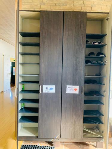 a closet with two doors and shelves with shoes at Village BFH in Omura