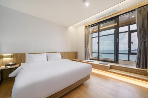 a bedroom with a large white bed and a large window at The Van Hotel in Ulsan