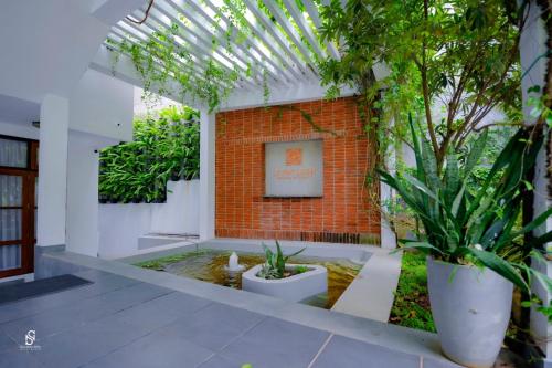 a courtyard with plants and a brick wall with a picture at Livin Lush Luxury Retreat in Anuradhapura