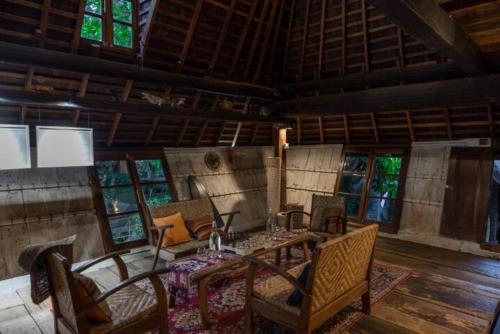 a dining room with a table and chairs and windows at Resort JUNGLEROOM Canggu in Canggu