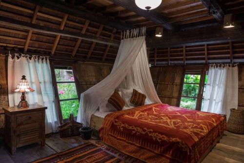 a bedroom with a bed in a room with windows at Resort JUNGLEROOM Canggu in Canggu