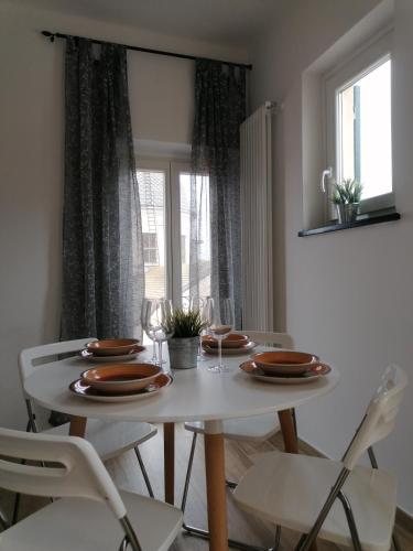 a white dining room table with plates and wine glasses at Casa Bartelli - Ceriale in Ceriale