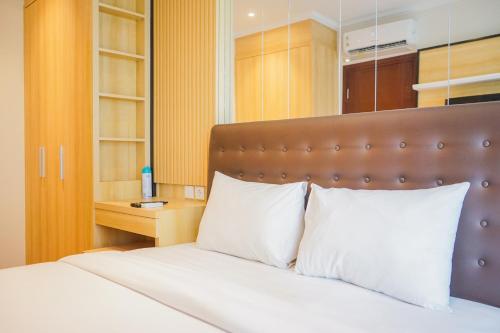 a bedroom with a bed with a brown headboard and white pillows at Cozy 3BR Asatti Apartment near ICE BSD By Travelio in Tangerang