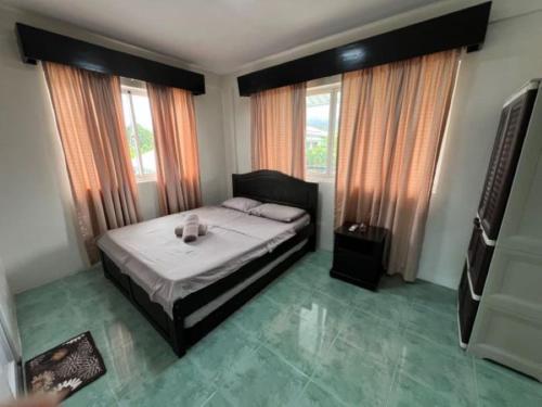 a bedroom with a bed and two windows at Casa Cecilia Hotel in Bantay