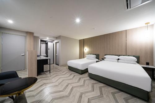 a hotel room with two beds and a desk at Seosan Hotel Posto in Seosan