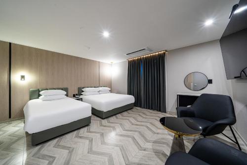 SeosanSeosan Hotel Posto的有两张床和一把椅子的酒店房间